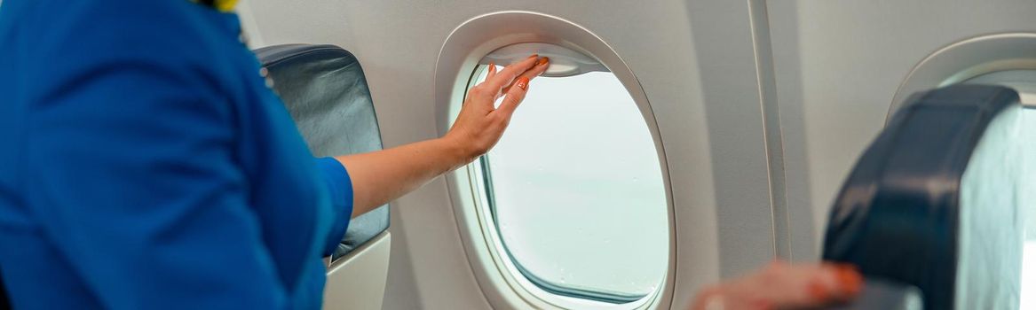 Close up of woman stewardess air hostess closing window in commercial passenger aircraft