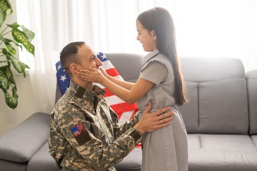 a child girl hugs a military father. dad in military uniform with his daughter. the veteran's return to the family.