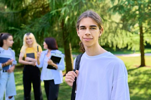 Male student 16, 17 years old with backpack, group of teenagers talking with teacher in school park. Back to school, back to college, high school, education, adolescence, teenage students concept