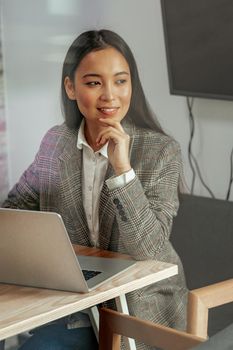 Portrait of smiling beautiful business asian woman working in office use computer and looking away