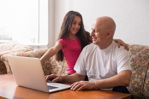 Grandfather adult granddaughter spend time together use laptop, browse website, younger generation teach explain to older how to use modern tech concept.