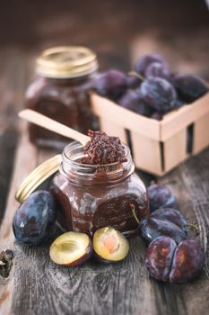 plum jam in glass jar with spoon on wooden background. High quality photo