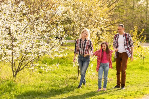 Happy family spending good time together in spring in a flowering garden.