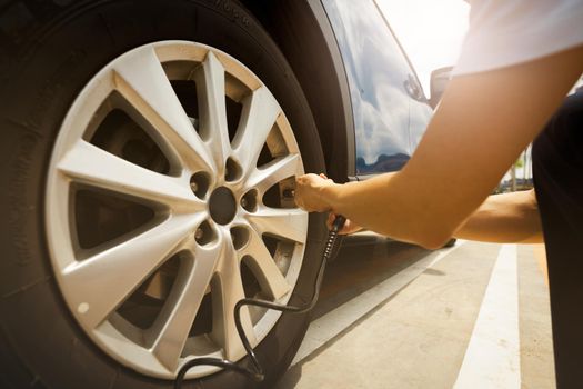 Woman inflates the tire. Woman checking tire pressure and pumping air into the tire of car wheel. Car maintenance service for safety before travel. Tire inflating point. Filling air in the tyre of car