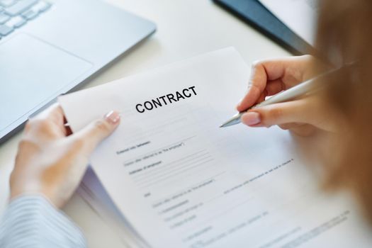 Close up of a hand holding a pen and signing a contract