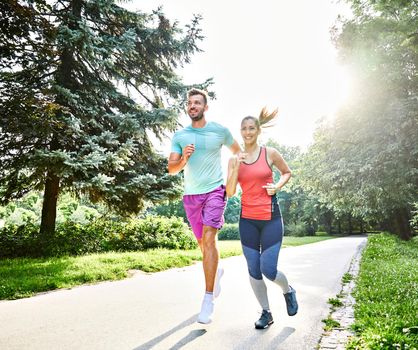 Portrait of a young couple running and exercising in a park outdoors