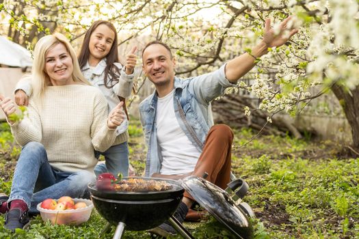 Happy family having a barbecue in their garden in spring. Leisure, food, family and holidays concept
