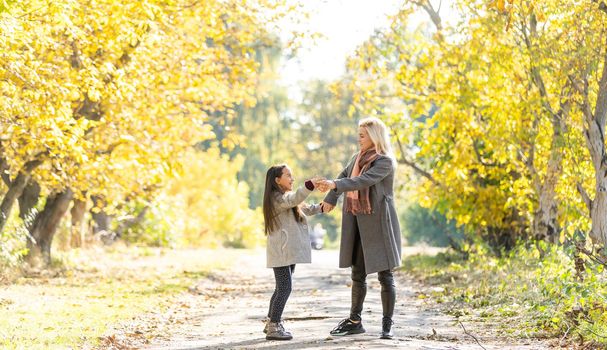 Mom with her daughter during autumn.