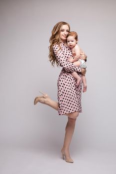 A beautiful family with a small child in the studio on a gray background