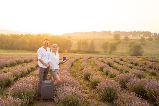 man and woman with suitcase in lavender field.