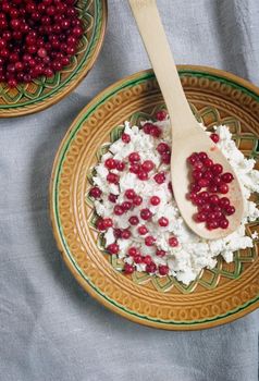 On the table in a ceramic plate delicious natural cottage cheese with red currant berries. close-up, top view.