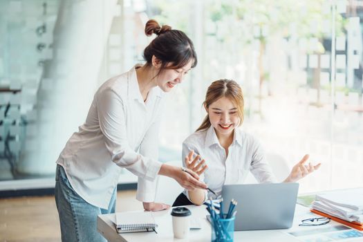 Negotiation, Analysis, Discussion: Portrait of an Asian female economist and marketer using computer laptop to plan investments and financial to prevent risks and losses for the company.