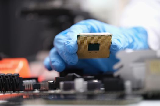Engineer holds in hands powerful processor or board after repair. CPU on computer motherboard concept