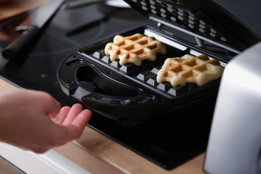 Waffle pastry baking on waffle maker machine closeup. Making waffles at home concept