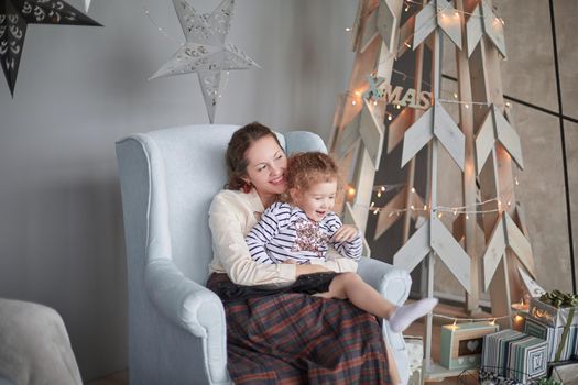 mom and daughter sitting in a chair in a modern living room. the concept of Christmas