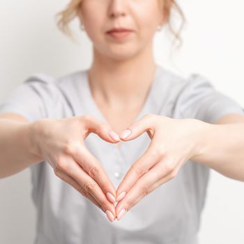 Close up of female hands of doctor making heart shape. Romantic concept.