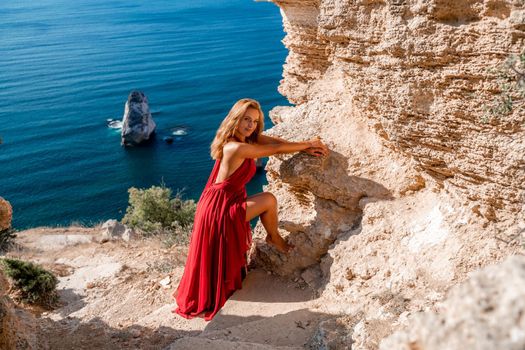 A woman in a red flying dress fluttering in the wind, against the backdrop of the sea