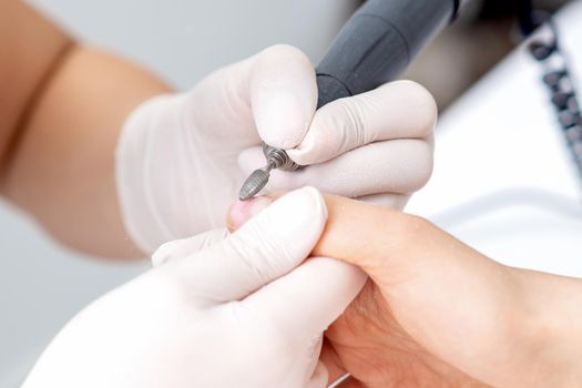Manicure master uses an electric nail machine to remove nail polish hands in nail salon