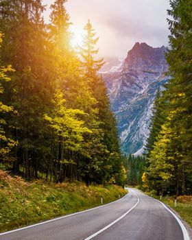 Mountain road. Landscape with rocks, sunny sky with clouds and beautiful asphalt road in the evening in summer. Vintage toning. Travel background. Highway in mountains.  