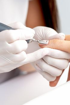 Manicure master uses an electric nail machine to remove nail polish hands in nail salon