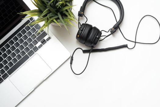 Laptop and headphones on a white background with copy space. Office concept. Flat lay, top view.