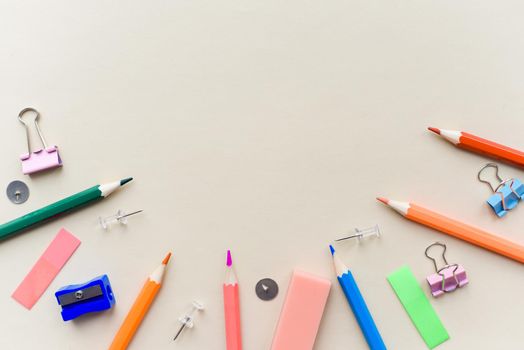 Top view blank office desk table with empty space on pastel beige backgroud. Flat lay. Paper clips, sharpener, pencils, stickers and other school supplies.