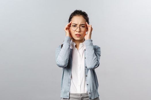 People, emotions and lifestyle concept. Distressed, tired asian woman overworking, having breakdown or emotional burnout, grimacing feeling pain in temples, headache or suffer migraine, grimace.