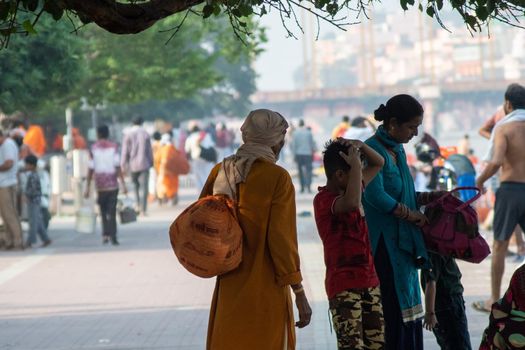 Haridwar, Uttarakhand - circa 2021 : Sadhu monk wearing the saffron robes holy to hinduism and a bag with holy symbols while walking among people on the banks of the sacred river ganga yamuna