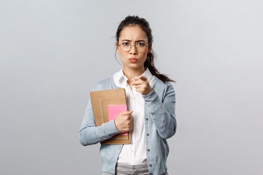 Education, teachers, university and schools concept. Portrait of angry displeased young female tutor scolding student bad behavrious, blame someone point fingers, frowning displesed, carry notebooks.