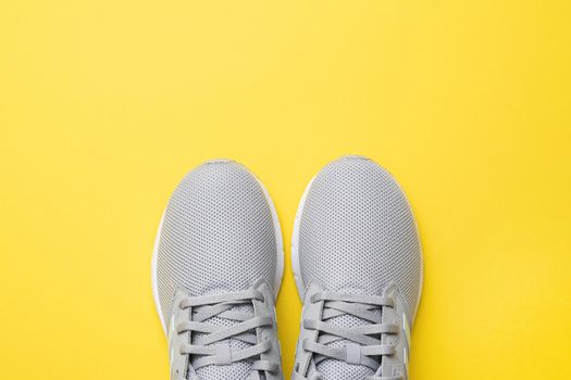 A pair of sneakers for fitness or running on a yellow background. Flat composition. The concept of sport, fitness, healthy lifestyle. Top view