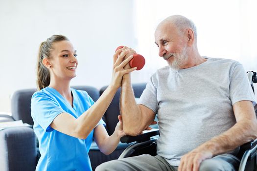 Doctor or nurse caregiver exercise with senior man at home or nursing home