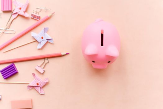 Concept of shopping to school. Stationery and piggy bank on a pink background.