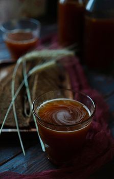 A glass of traditional homemade beverage kvass with rye spikelets and slices of rye bread, selective focus, close up.