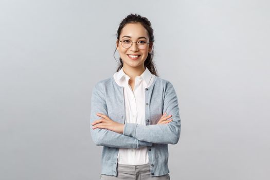 Career, business and education concept. Portrait of cheerful asian girl ready to start online lesson with students, explain class new theme, cross hands chest confident, smiling self-assured.