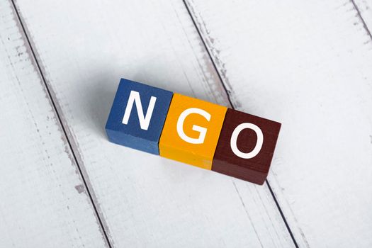 NGO acronym for Non-Governmental Organization on colorful wooden cube. Flat lay. Copy Space. Directly above.