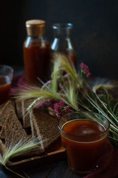 Traditional homemade beverage kvass in glass and bottles is a good summer cooling drink made from rye bread, selective focus, low key.