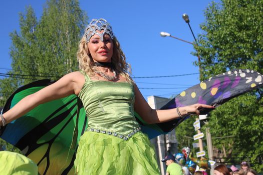 Beautiful blonde on stilts in a butterfly costume and a crown. Carnival..