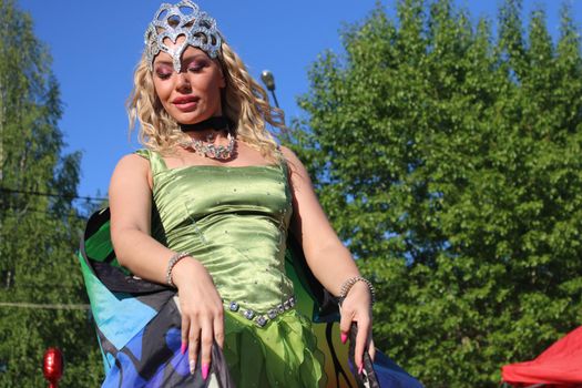 Beautiful blonde on stilts in a butterfly costume and a crown. Carnival..