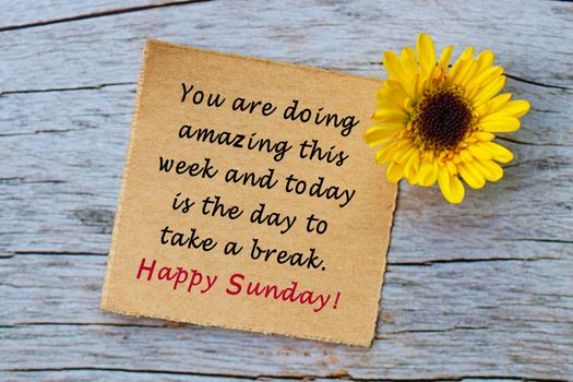 Motivational quote on torn brown paper on wooden surface. You are doing amazing this week and today is the day to take a break, happy sunday.