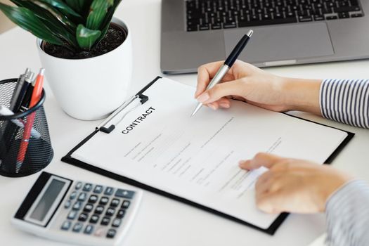 Close up of a hand holding a pen and signing a contract