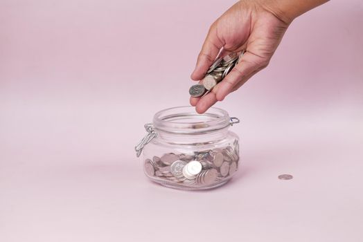 young man saving coins in a jar white sited .