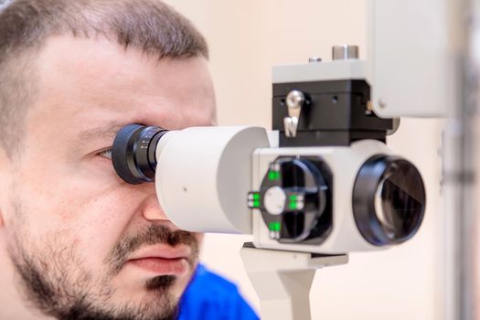 A male ophthalmologist checks a patient's vision with a modern device with a light beam.