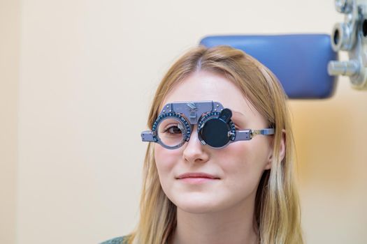 A male optometrist checks the eyesight of a young girl with a trial frame.