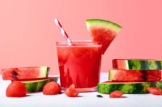 Close-up fresh watermelon juice or smoothie in glasses with watermelon pieces on pink background. Refreshing summer drink.