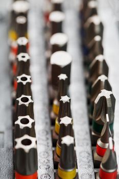 A set of metal power bits in a box on a gray background, for repair and maintenance