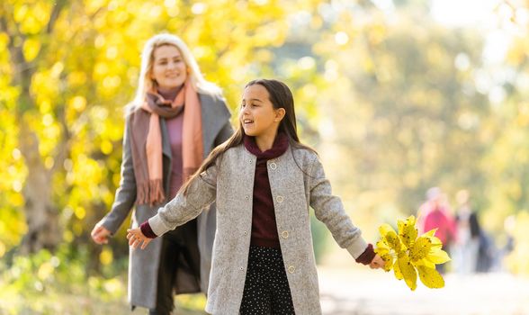 Young mother playing with her daughter in autumn park.