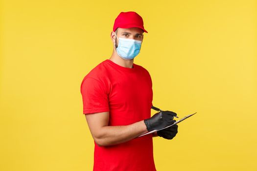 Express delivery during pandemic, covid-19, safe shipping, online shopping concept. Employee in delivery company storage writing down packages info, tracking order information on clipboard.