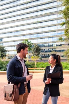 smiling coworkers chatting in the park in front of the office building, concept of work and business lifestyle, copy space for text