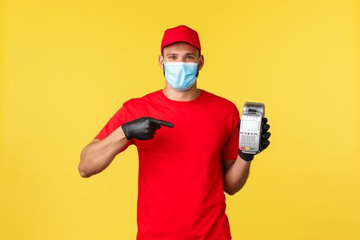 Food delivery, tracking orders, covid-19 and self-quarantine concept. Courier recommends using POS terminal for safe contactless paying during coronavirus pandemic, yellow background.