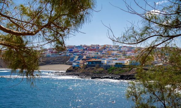 15 february 2022-El Hombre beach in Gran Canaria located at the bottom of the town with beautifully coloured houses and black volcanic sand